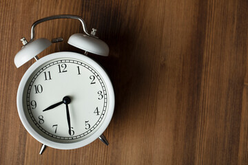 Retro alarm clock on wooden background. back to work and school concept.