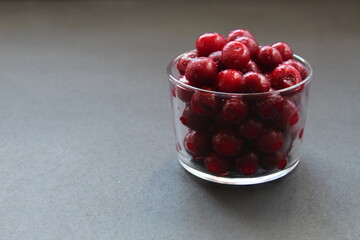 Food photo frozen cherries or cherries in a glass glass tableware on a black background with a place for text to eat a copyspace