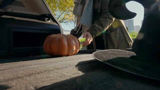 view from car woman puts pumpkin in witch hat shopping halloween slow motion