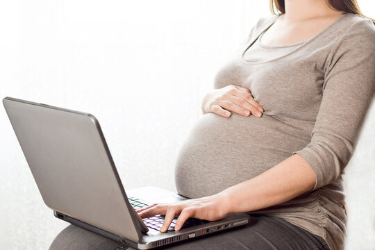 Pregnant woman using laptop at home, remote working or surfing internet. Pregnancy And Technology. Pregnant Lady Browsing Internet, Shopping Online, Reading Maternity Blog, Cropped Image, Free Space