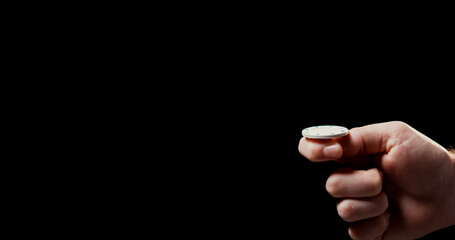 Close up of male hand flipping white poker chip with black background