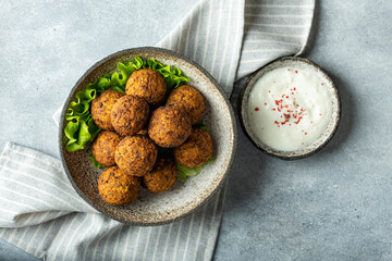 falafel balls in a ceramic bowl on a concrete background, top view