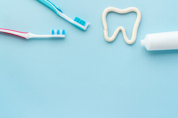 Tooth shape with tube of toothpaste and toothbrush. Dental hygiene concept, top view