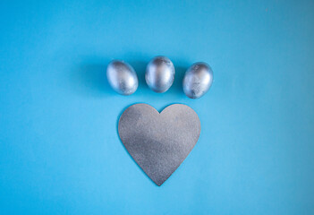 Obraz premium Silver eggs and decorative silver heart on delicate blue background. concept of rich Easter holidays, greeting cards and spring love.