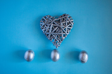 Silver eggs and decorative silver heart on delicate blue background. concept of rich Easter holidays, greeting cards and spring love.