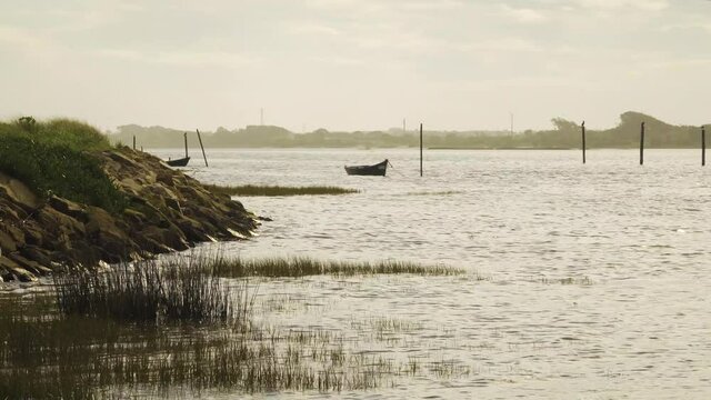 4K silhouettes of two boats anchored in the middle of the Ria de Aveiro, estuary of river Vouga, 60fps.