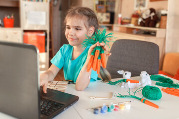 Girl with DIY carrot with wooden clothe pins greeting family with Easter online, zero waste holidays