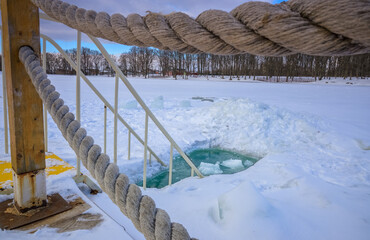 Obraz premium Bridge over the river surrounded by rope. Ice-hole for winter swimming.