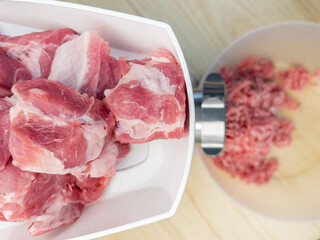 Meat grinder. Making homemade raw minced meat at kitchen. Close up of fatty pork minced.