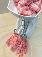 Meat grinder. Making homemade raw minced meat at kitchen. Close up of fatty pork minced.