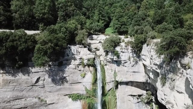 Aerial Forward: Tourists On Rocky Cliff By Waterfall In Forest