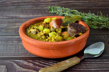 Lentil stew with chorizo and blood sausage, served in a clay plate. Typical of Spanish cuisine.
