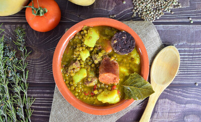 Typical of Spanish cuisine. Lentil stew with chorizo and blood sausage, served in a clay plate. Zenith view.