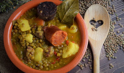 Lentil stew with chorizo and blood sausage, served in a clay plate. Typical of Spanish cuisine.