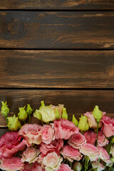 pink eustoma and rose flowers on wooden surface