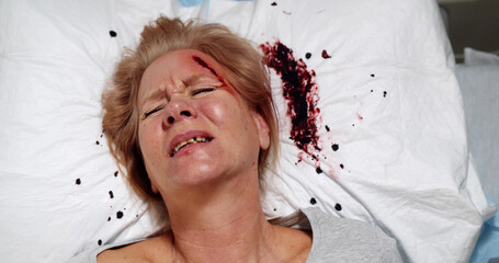 Top view of injured woman screaming lying on hospital bed with blood stains