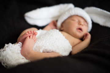 newborn baby in a bunny costume, close up , black background, defocus background