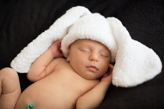 newborn baby in a bunny costume, close up , black background