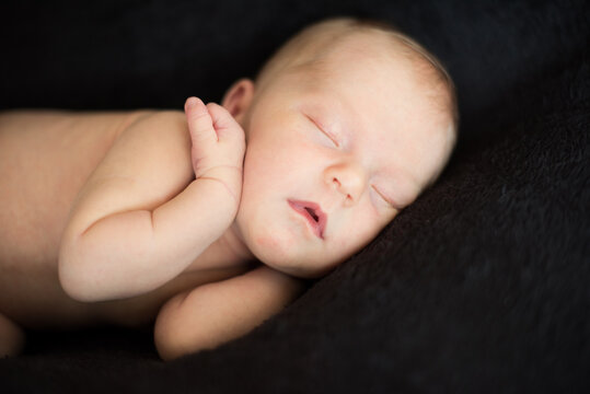 Newborn sleeping baby on black background. Close-up.