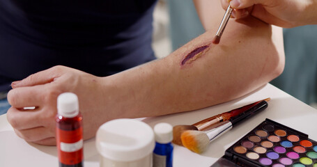 Close up of professional making fake wound makeup special effect on arm