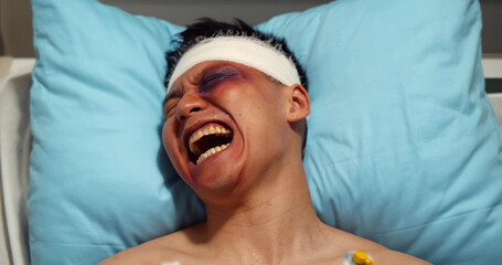 Injured young male patient with bruises on his face screaming in agony