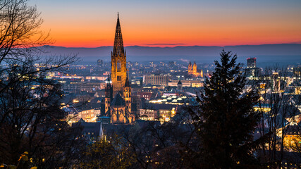 Germany, Freiburg im Breisgau, Magical red sunset sky above skyline of the beautiful city and muenster by night in blue hour atmosphere
