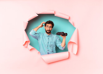 young crazy bearded man. thinking or doubting expression. binoculars concept