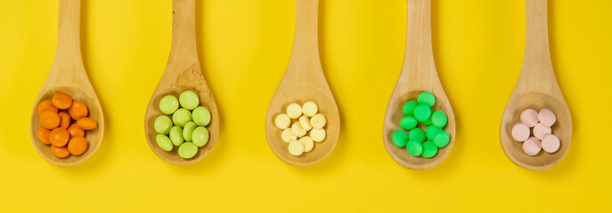Mixed herbal tablets on a wooden spoon. Food supplement. Selective focus