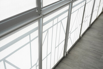 White fabric roller blinds on the plastic window on a balcony in the living room.