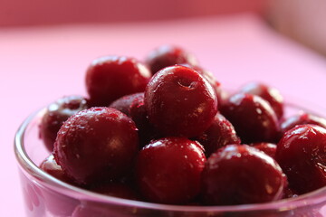 cherry in a glass on a pink red background with a place to text the view from the side close-up of the copyspace