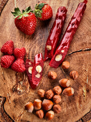 Fototapeta na wymiar slicing Churchkhela, strawberries and nuts on a wooden background, top view, serving
