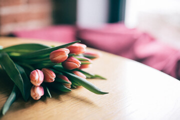 A bouquet of red tulips is on the table in the cafe. Comfortable pillows on the sofa
