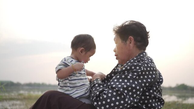 Asian Grandmother and Grandson sitting and playing In Park together in the garden.Happy Asian family conception.
