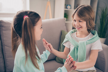 Photo portrait of small children clapping hands playing game smiling cheerful happy on cozy sofa
