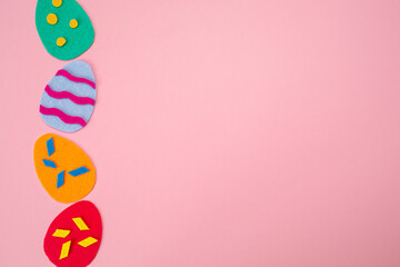 Obraz na płótnie Canvas Easter decorations. Cut out of felt applications of colourful eggs on pink background. Flat lay. Copy space. Holiday concept