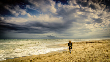 Einsamer Mensch geht am Strand bei Gewitter Bew&ouml;lkung