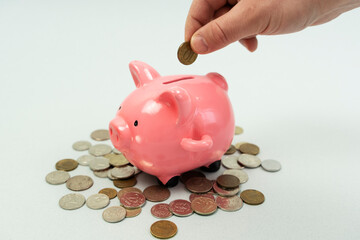 piggy bank business standing on a pile of coins concept. A hand is putting a coin in a lifestyle piggy bank on a yellow background. saving money is an investment for the future. Banking investment