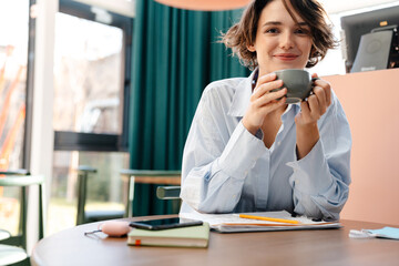 Young smiling attractive lady drinking coffee