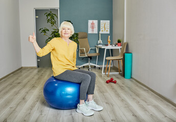 Senior woman showing thumbs up while training at a wellness center