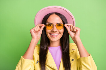 Photo portrait of amazed cheerful hispanic woman touching yellow sunglass smiling isolated on bright green color background