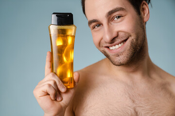Fototapeta premium Close up of a smiling young nude man presenting shampoo