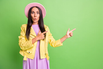 Photo portrait of amazed woman pointing looking at copyspace smiling staring in pink hat isolated on bright green color background