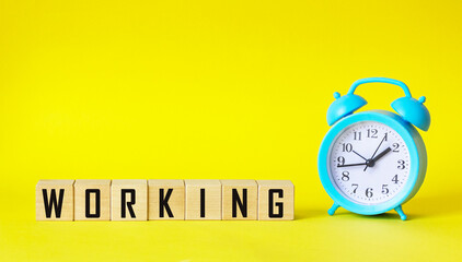 The word WORKING on a yellow background, next to a blue alarm clock
