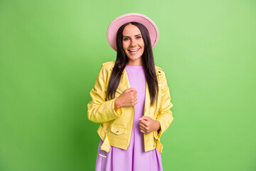 Photo portrait of brunette girl in pink hat yellow leather jacket smiling isolated on bright green color background
