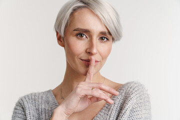 White-haired young woman showing silence gesture at camera