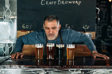 barman smelling fresh beer in glasses