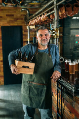 barman holding beers in wooden crate in bar