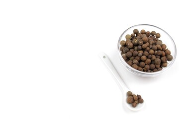 Pepper peas or spices in a bowl with spoon on a white background 