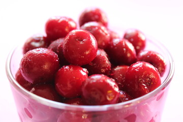 cherry in a glass on a pink red background with a place to text the view from the side close-up of the copyspace