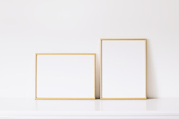Two golden vertical and horizontal frames on white furniture, luxury home decor and design for...